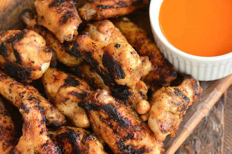 cooked grilled chicken wings on a wooden plate with buffalo sauce