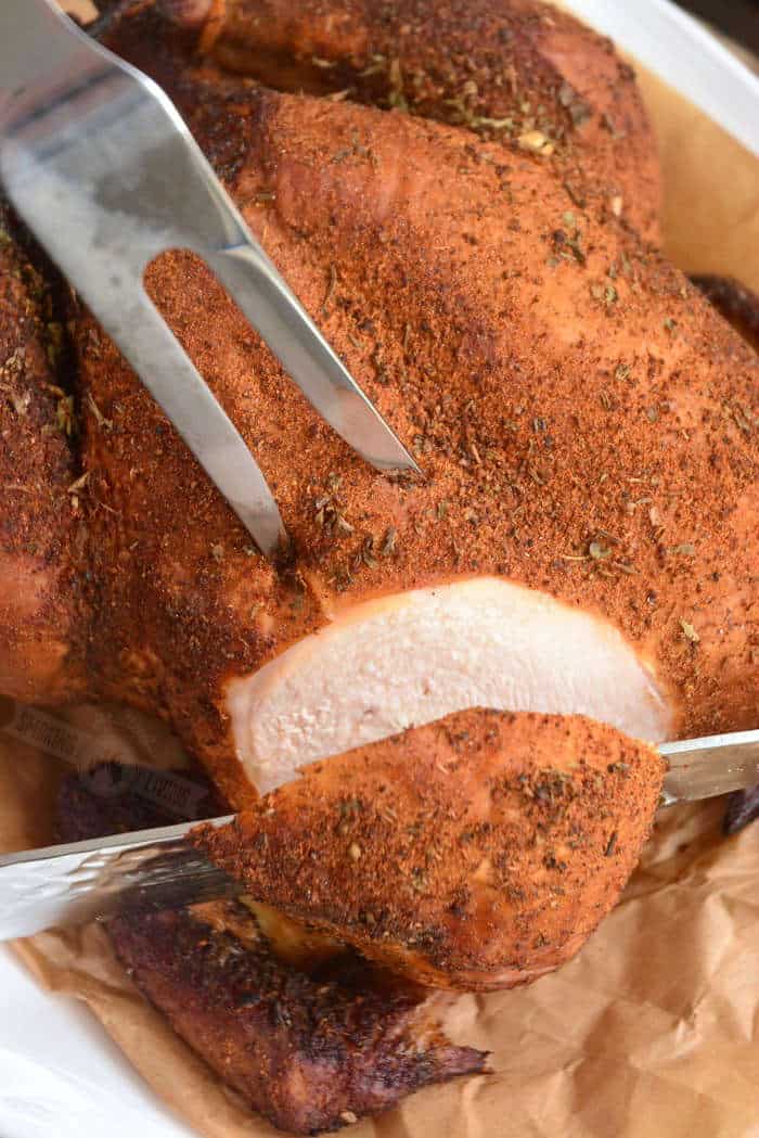 slicing into smoked chicken breast with a knife and holding with a fork