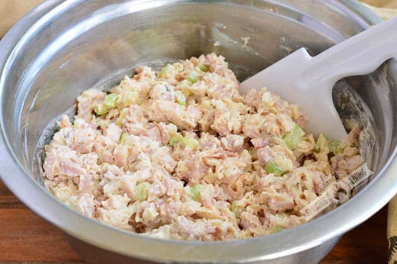 mixed chicken salad in a metal mixing bowl with white spatula