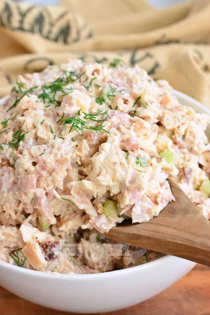 scooping chicken salad with a wooden spoon