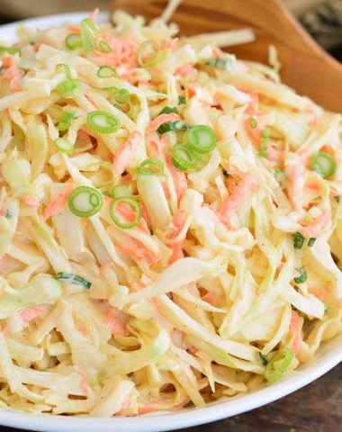 horizontal view of coleslaw in a bowl with a wooden spoon next to it
