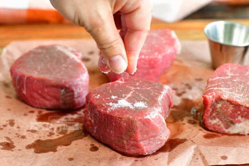 adding salt to a fillet with three others on the background