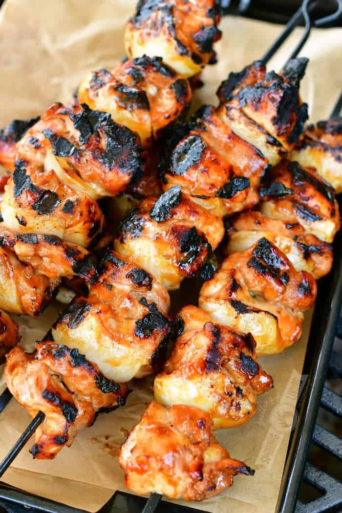 skewers of cooked chicken pieces on a black tray with parchment paper