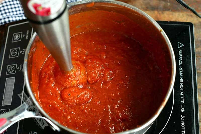 blending the sauce in a pot with an immersion blender