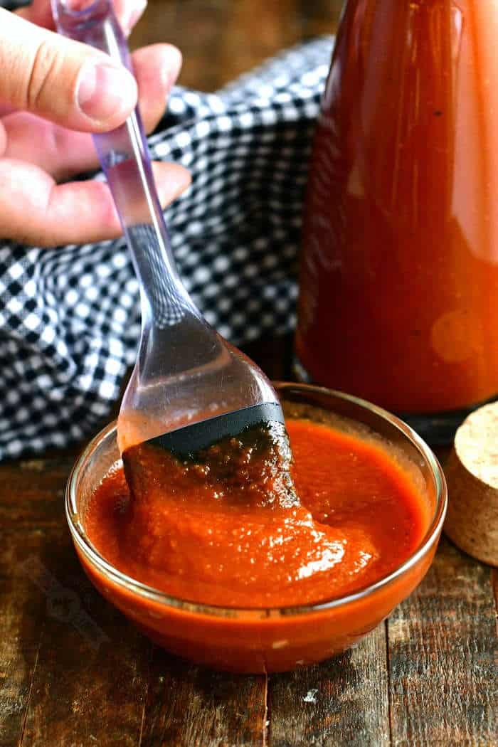 stirring a bowl of bbq sauce with a whisk