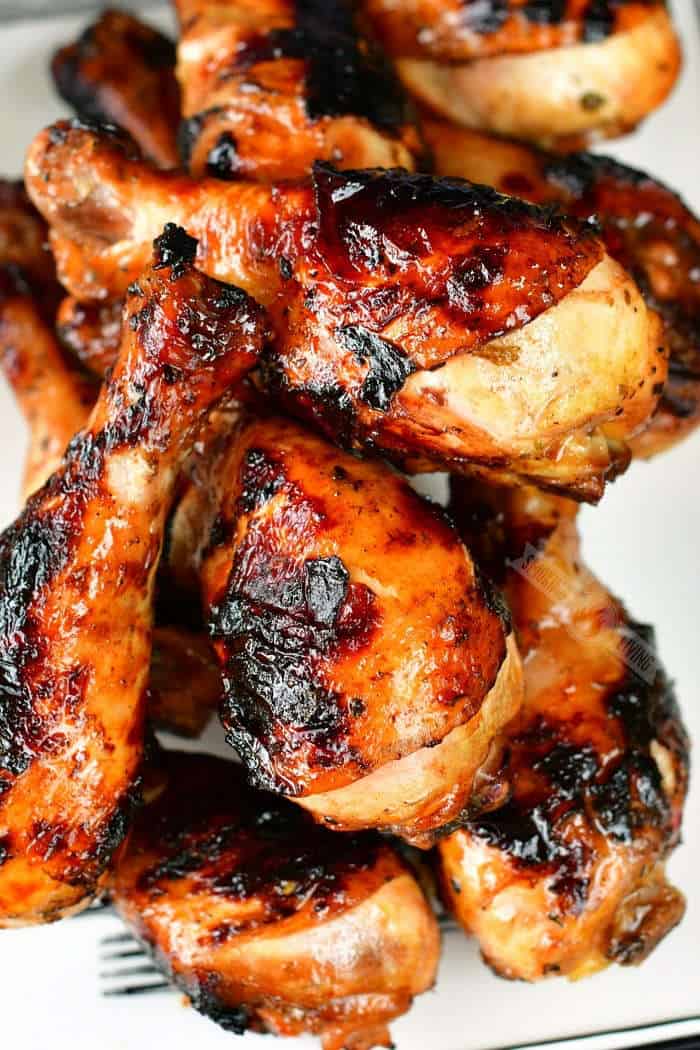 top view of grilled chicken legs stacked on top of each other on a white plate