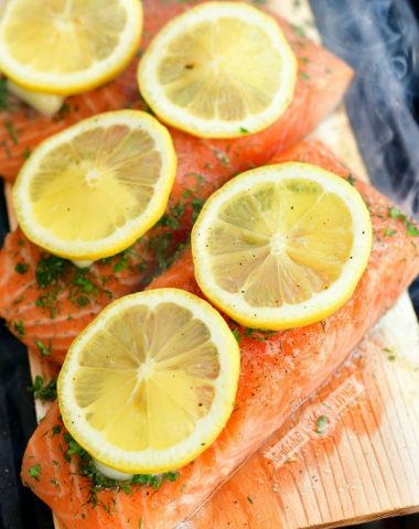 uncooked salmon fillets with lemon and herbs on top on a wooden plank