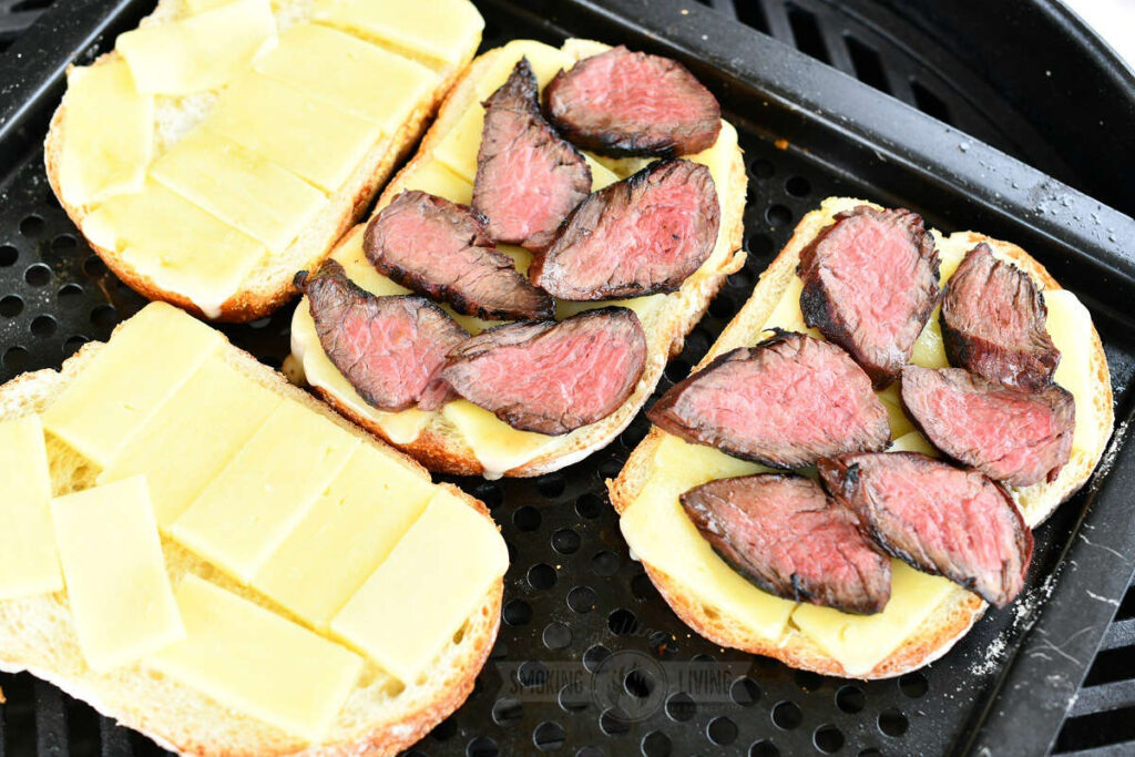 four slices of bread topped with slices of white cheddar cheese and sliced steak