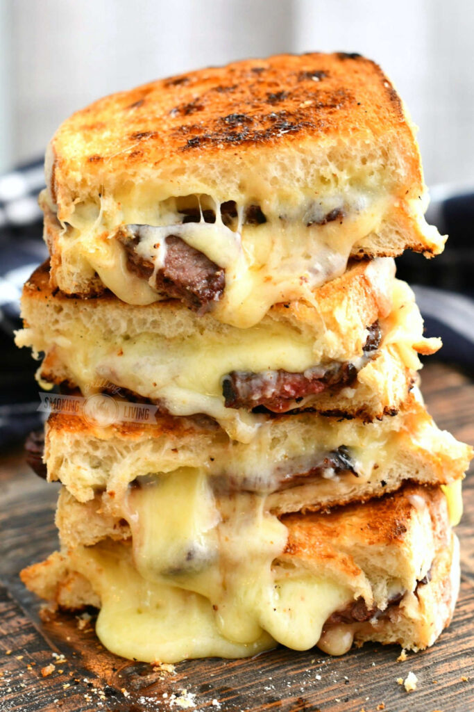side view of 4 steak grilled cheese halves stacked on to of each other