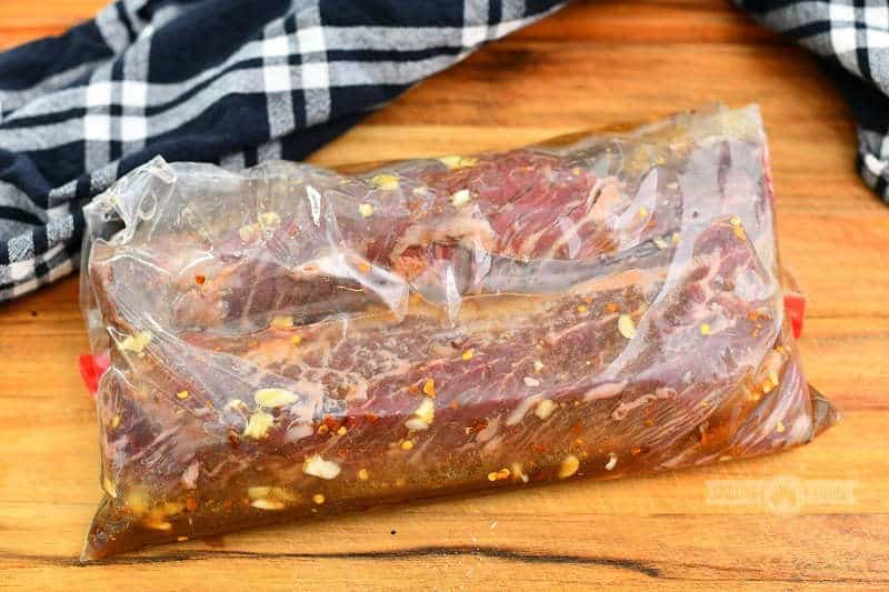 two hanger steaks in a plastic bag with steak marinade