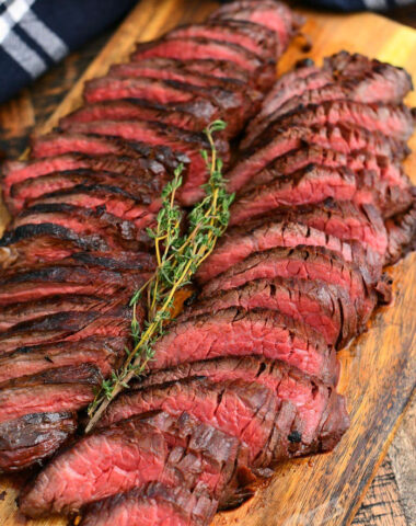 thinly sliced hanger steaks on a cutting board with a sprig of thyme on top