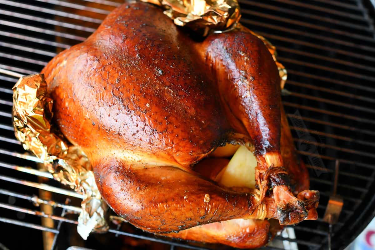 cooked turkey on the smoker with wings wrapped with foil