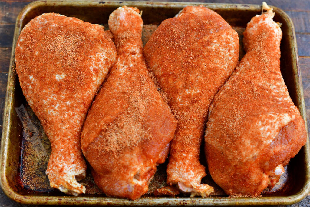 seasoned uncooked turkey legs on the baking pan before smoking
