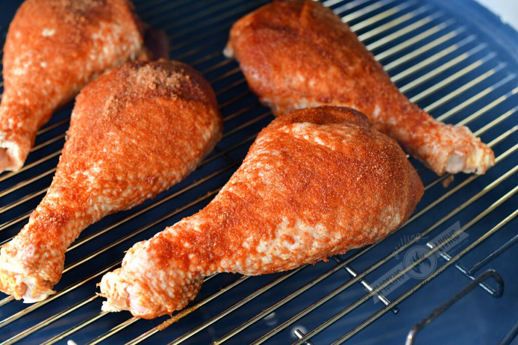 uncooked turkey legs seasoned and placed on the smoker