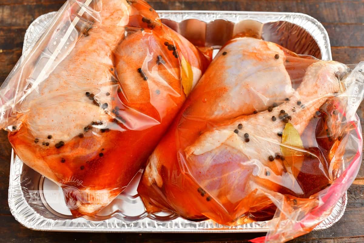 turkey legs in brine in plastic bags inside an aluminum pan