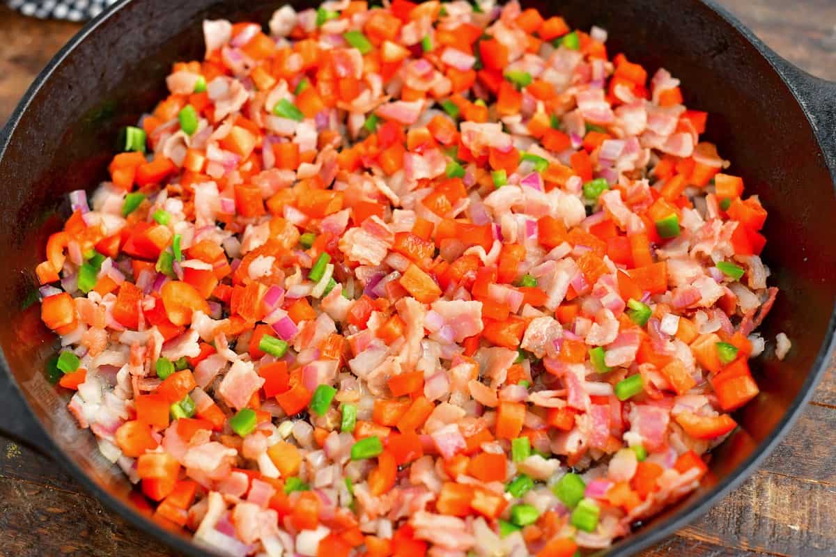 bacon, bell peppers, red onion, and jalapenos diced and cooking in a skillet