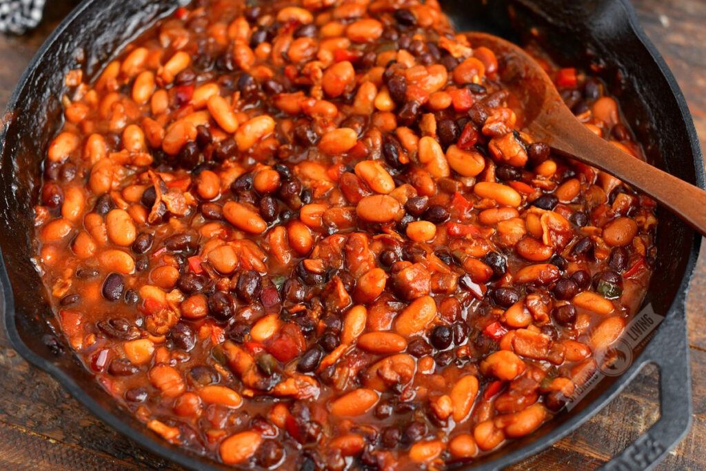 smoked beans in bbq sauce in a skillet with a wooden spoon