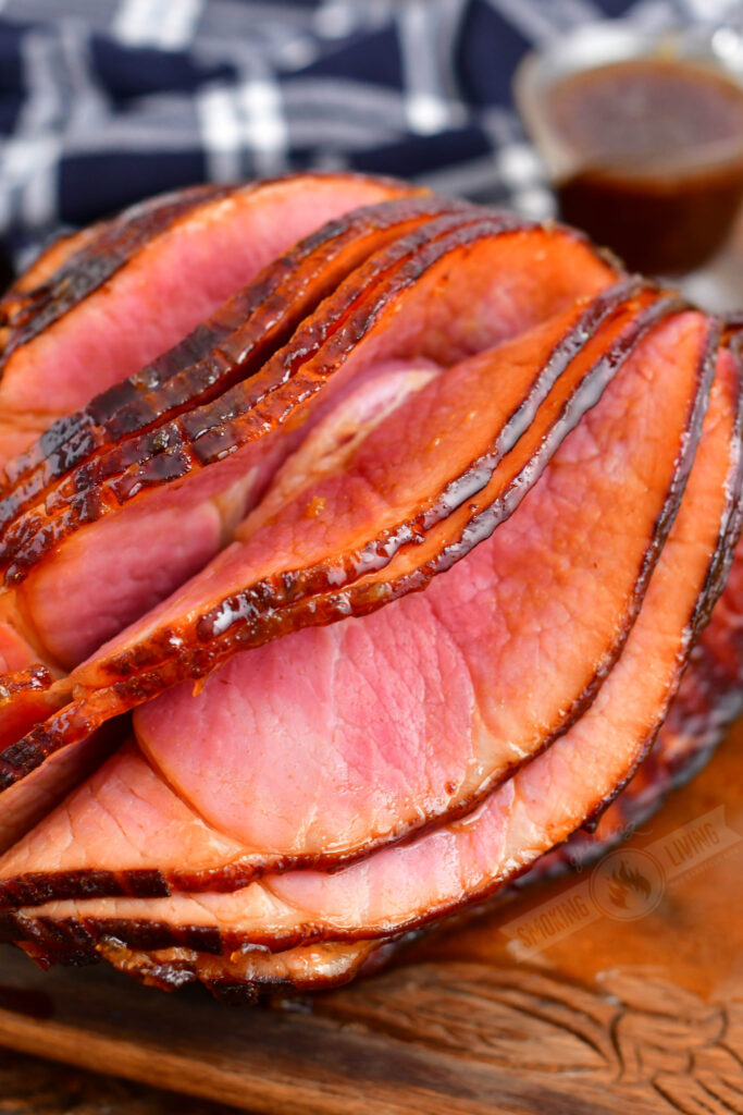 slices coming off of the smoked ham with glaze on the background
