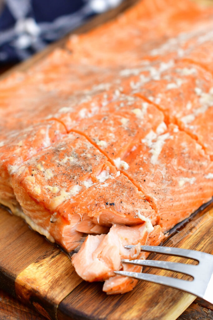 cutting into a smoked salmon filet with a fork