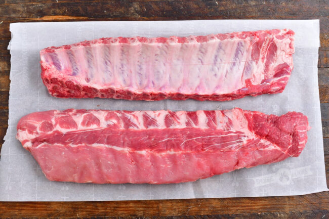 two racks of raw baby back ribs on the parchment paper