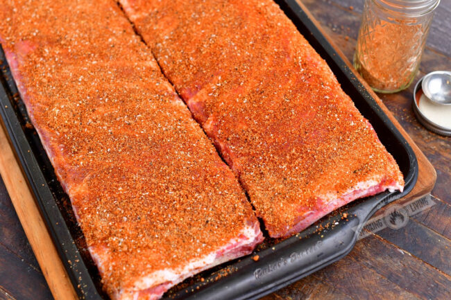 raw St. Louis cur ribs coated in a dry rub in a metal baking sheet