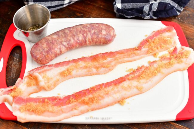 two bacon strips with brown sugar and sausage on a board