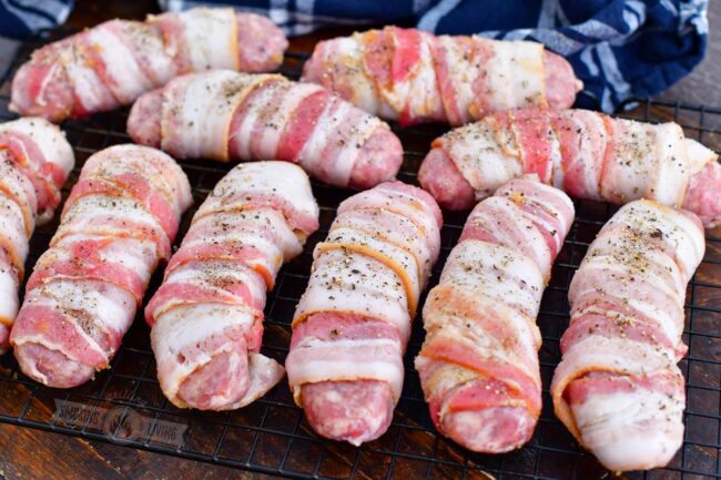 uncooked bacon wrapped sausages sprinkled with pepper