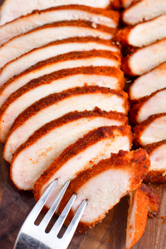 poking slices of smoked chicken breast with a fork