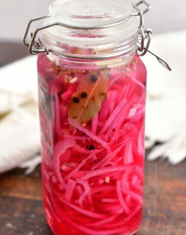glass jar with bright pink liquid, red onions, and seasoning