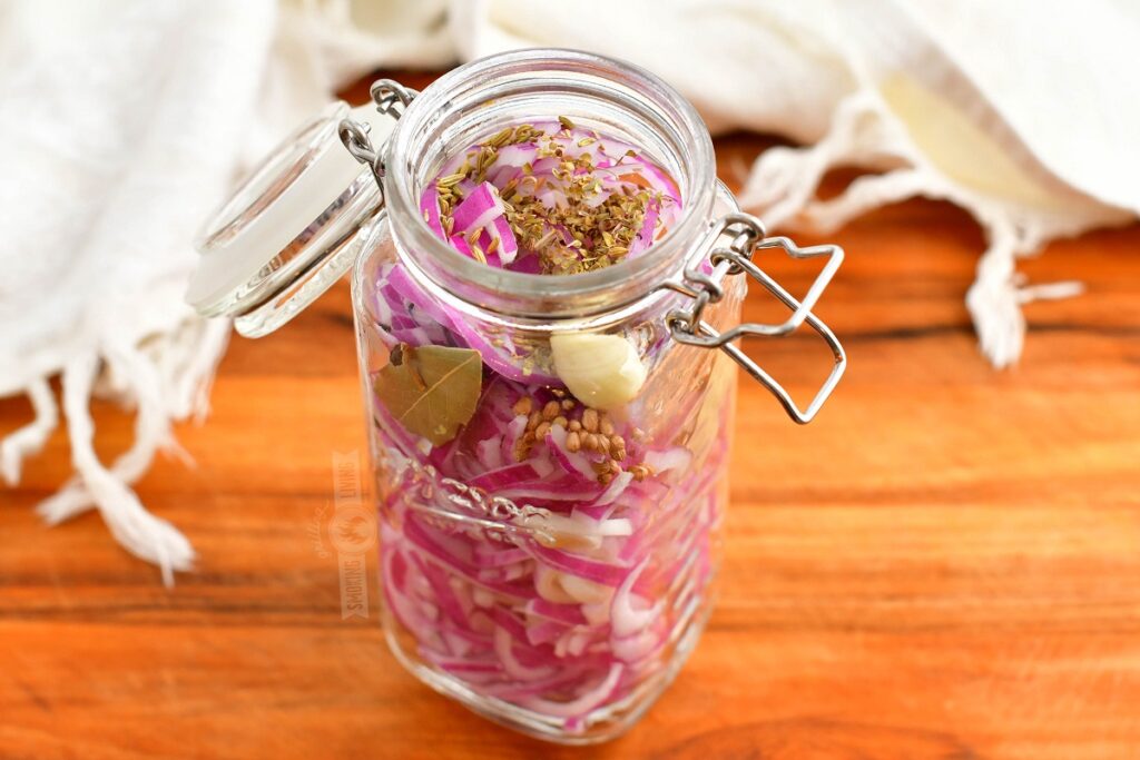 glass jar filled with red onions, garlic, and seasoning