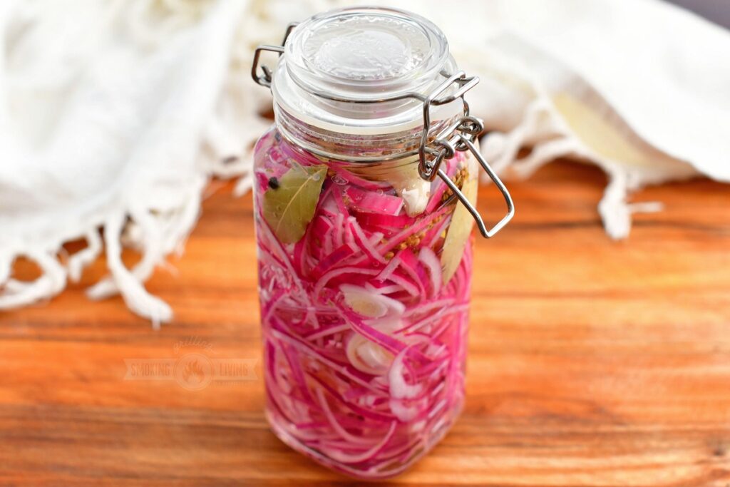 glass jar filled with sliced red onions and seasoning in liquid