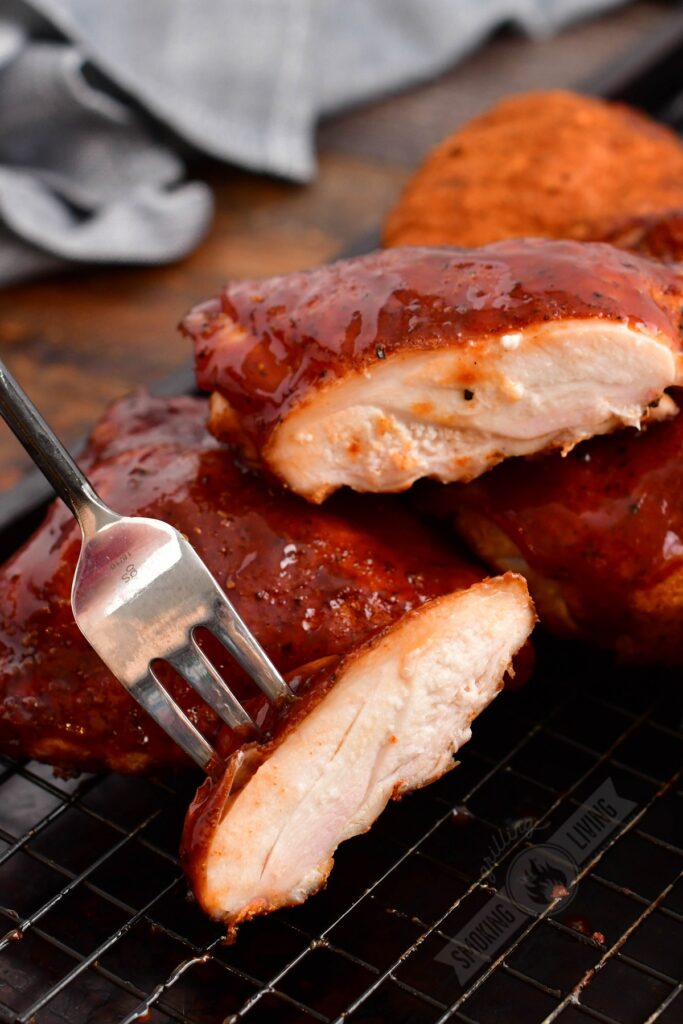 smoked chicken thigh cut in half with a fork holding one piece