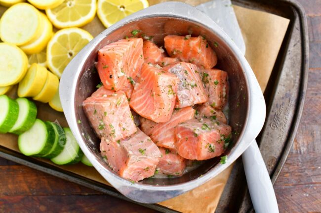 salmon pieces in a mixing bowl mixed with herbs and garlic marinade
