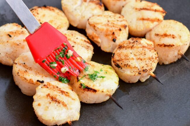 brushing grilled scallops with herbed butter