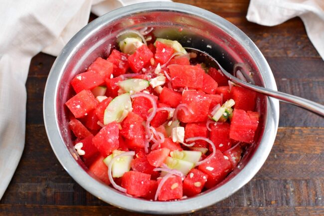 tossing watermelon, cucumber, onion, and feta in a bowl