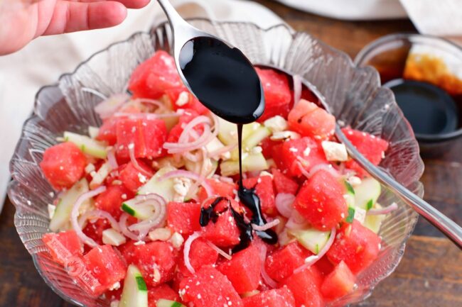 drizzling balsamic reduction over the watermelon salad