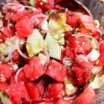 closeup of watermelon feta salad in a glass bowl with a spoon