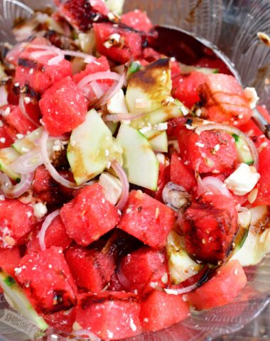 closeup of watermelon feta salad in a glass bowl with a spoon