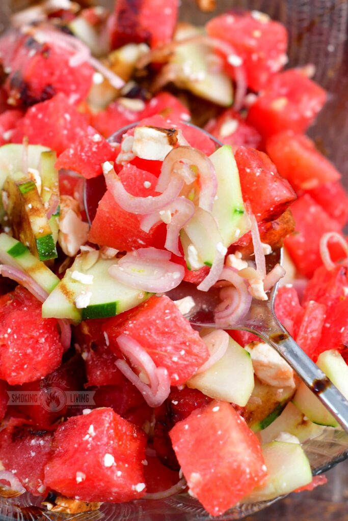 spooning watermelon salad with a silver spoon