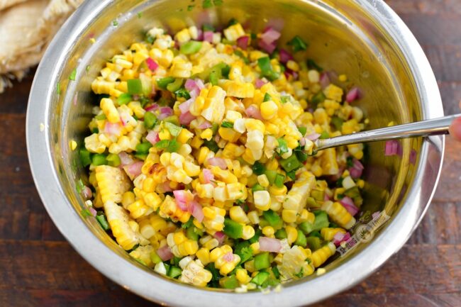 mixing ingredients for the corn salad in a metal bowl