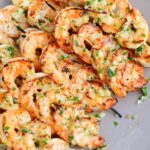 several shrimp skewers stacked on the grey plate