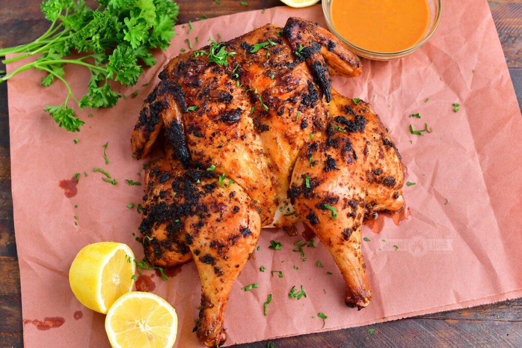 grilled whole butterflied chicken on butcher paper with lemon and parsley