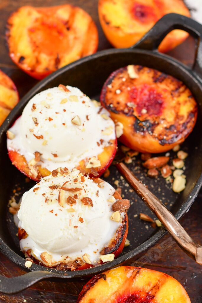 top view of grilled peaches topped with ice cream on a cast iron dish