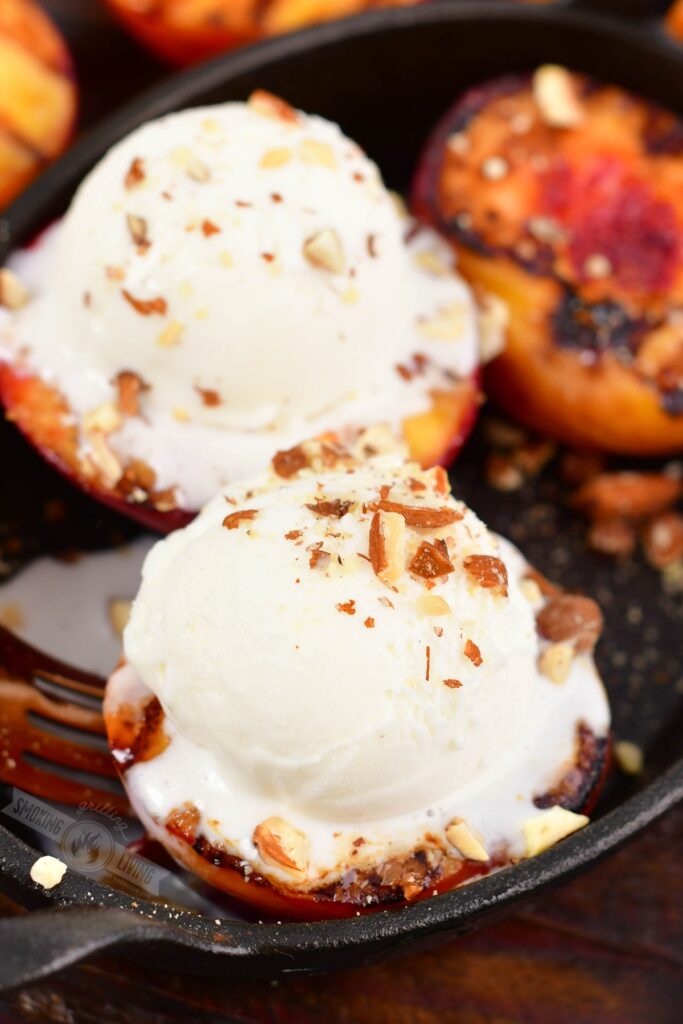 closeup of grilled peached topped with ice cream and nuts