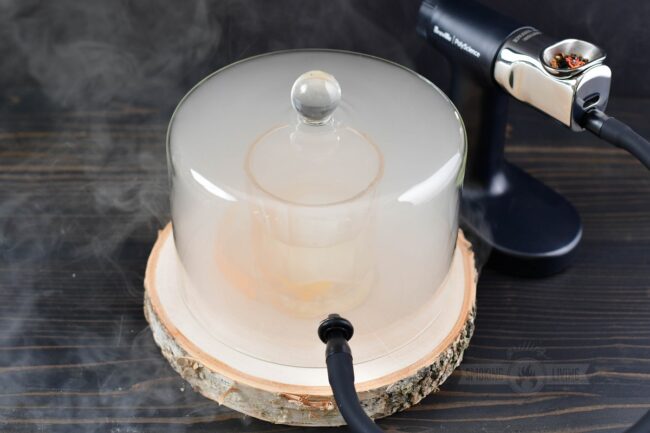cocktail under a cloche surrounded by smoke