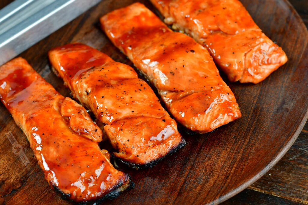 4 glazed grilled salmon filets on a wooden plate 