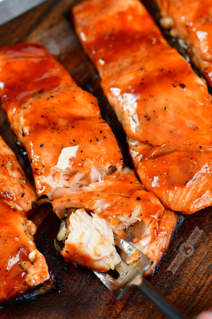 closeup of flaking off glazed grilled salmon with a fork