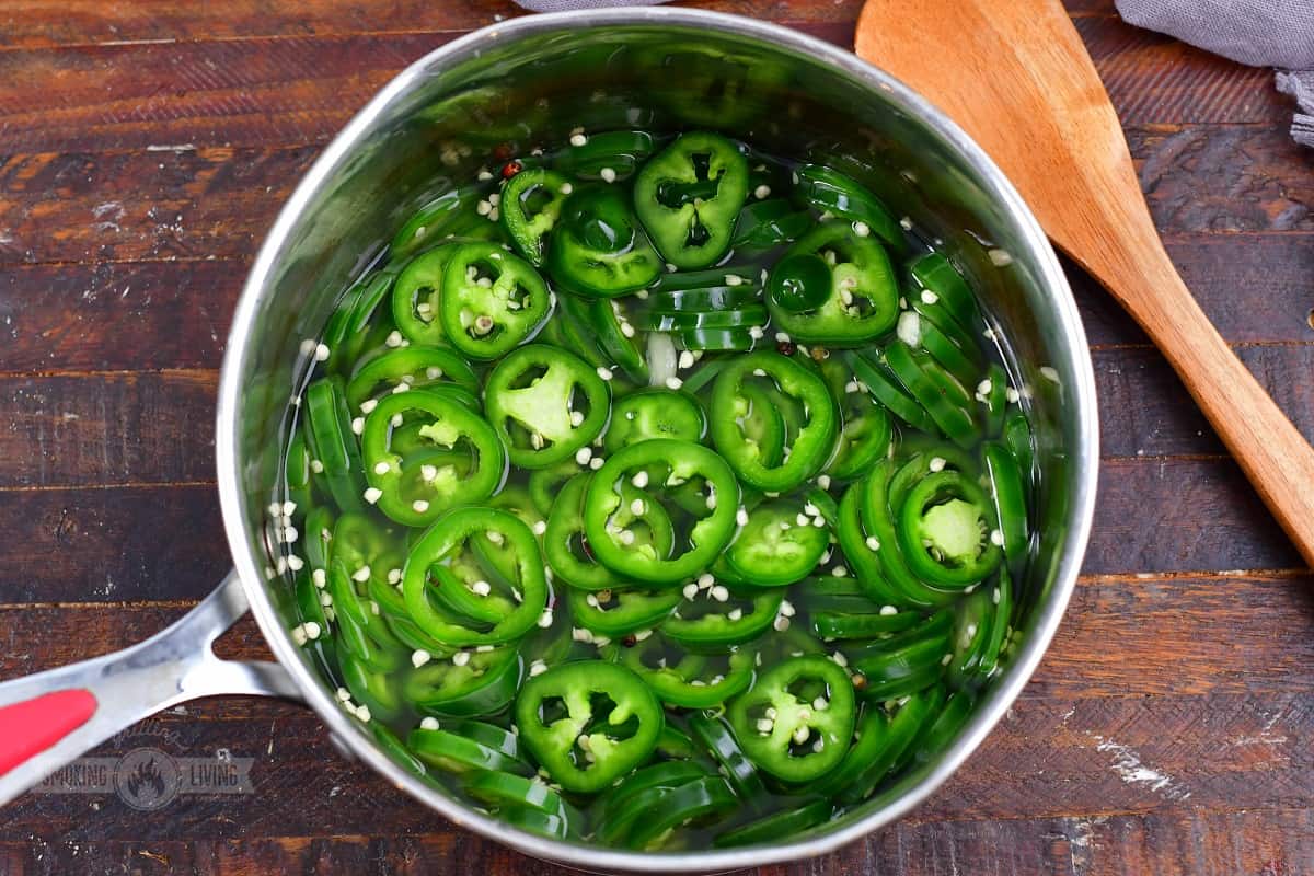 sliced jalapenos in a pot with pickling liquid and spices