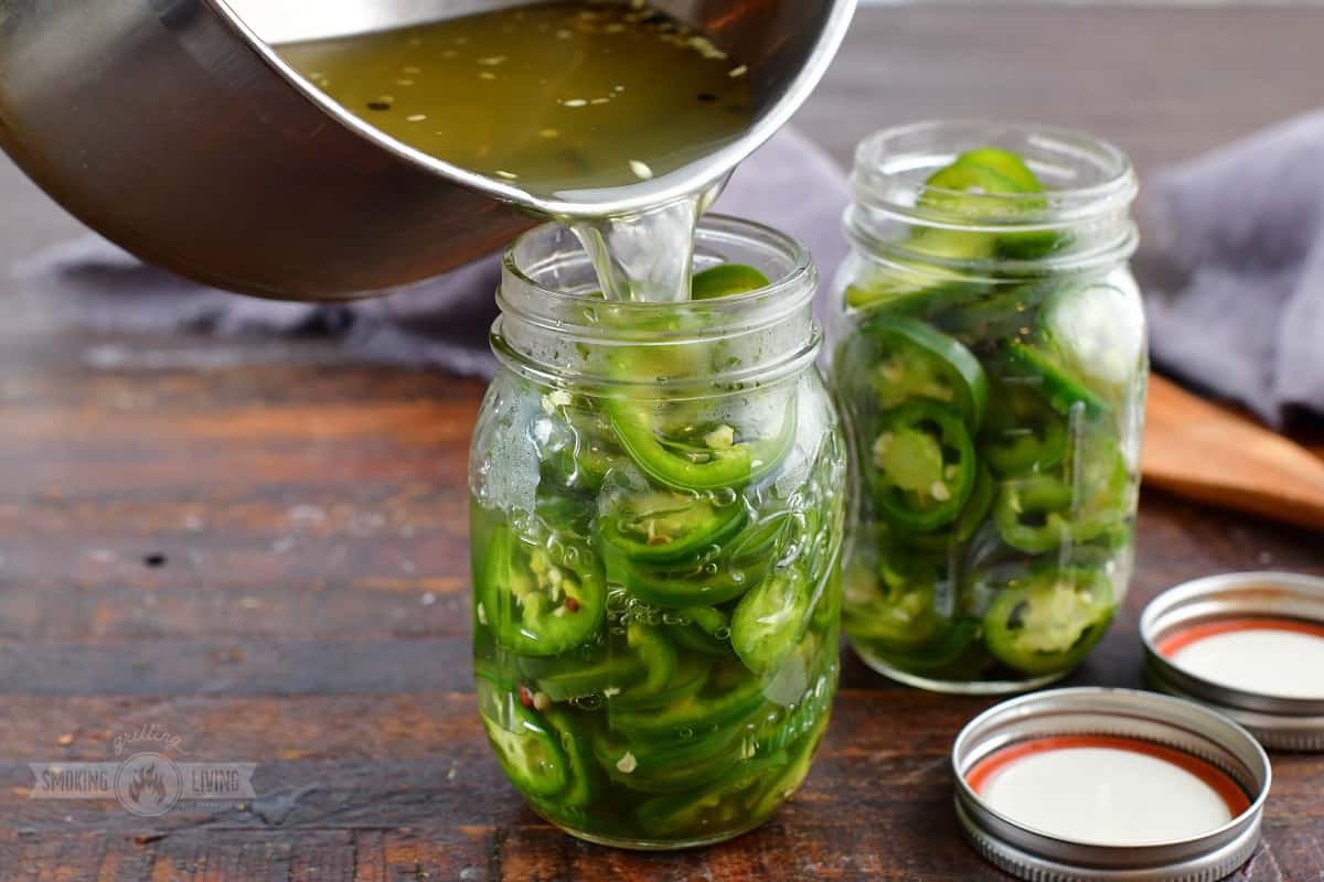 pouring pickling liquid into jar with jalapenos