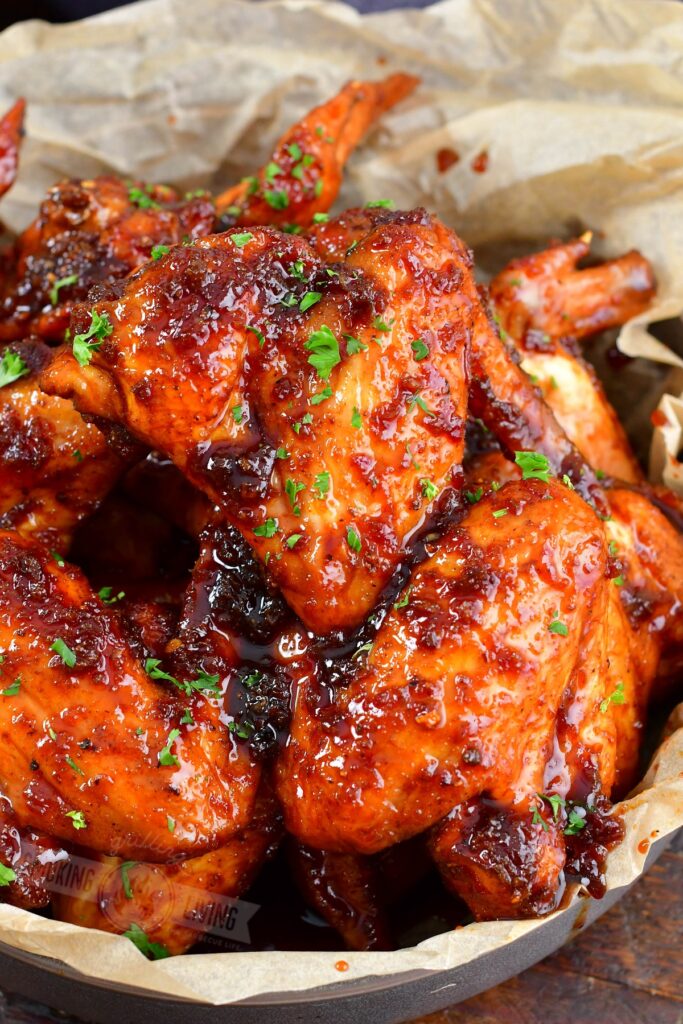 close view of two glazed chicken wings in a basket